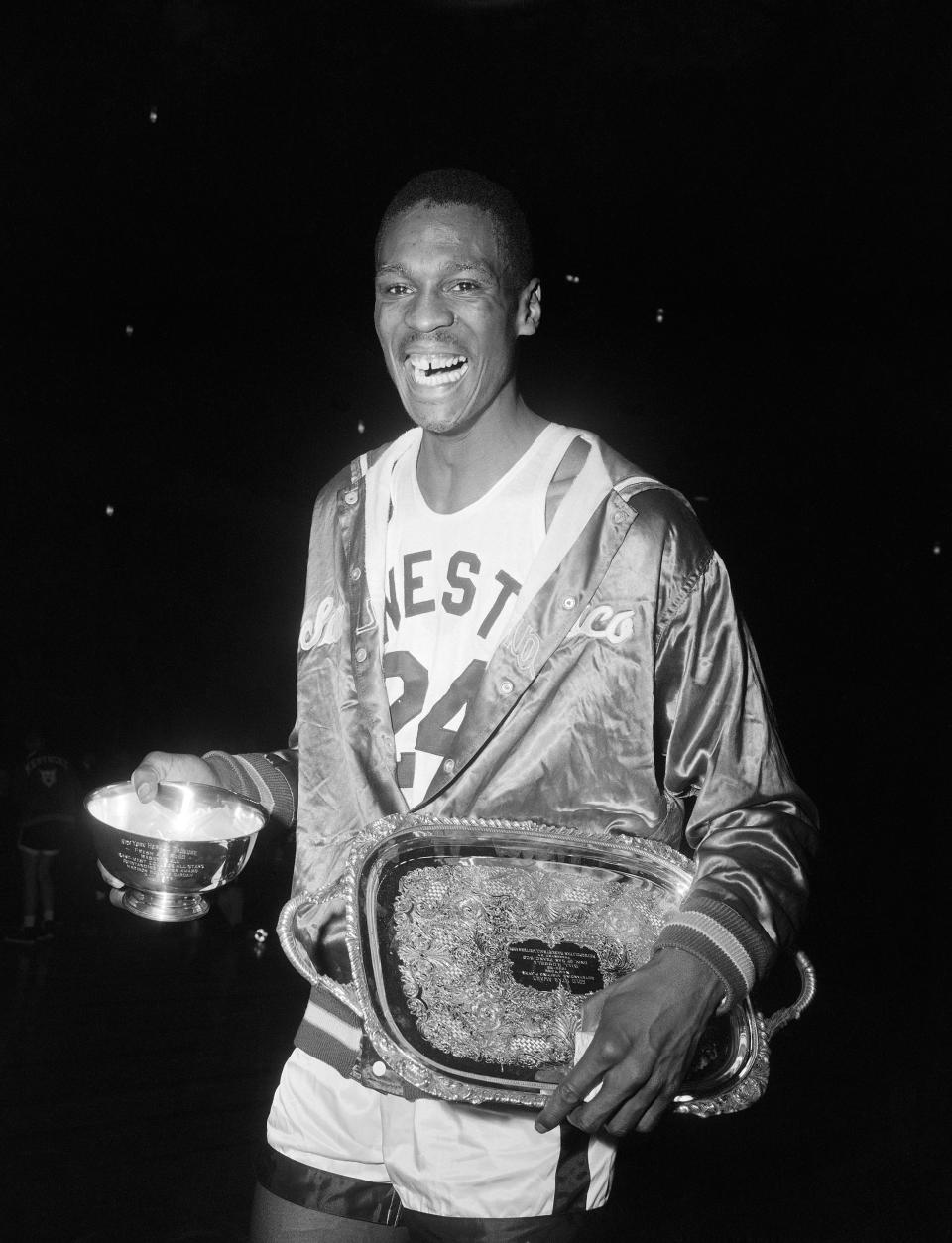 FILE - San Francisco NCAA college basketball player Bill Russell holds his Most Valuable Player trophies at Madison Square Garden in New York, March 31, 1956. The 6-foot-10 center had one of most dominating NCAA Tournament games in history during the 1956 title game, finishing with 26 points and 27 rebounds in a win over Iowa. He also was believed to have swatted at least a dozen shots, though blocked shots were not yet an official stat.(AP Photo/John Lent, File)