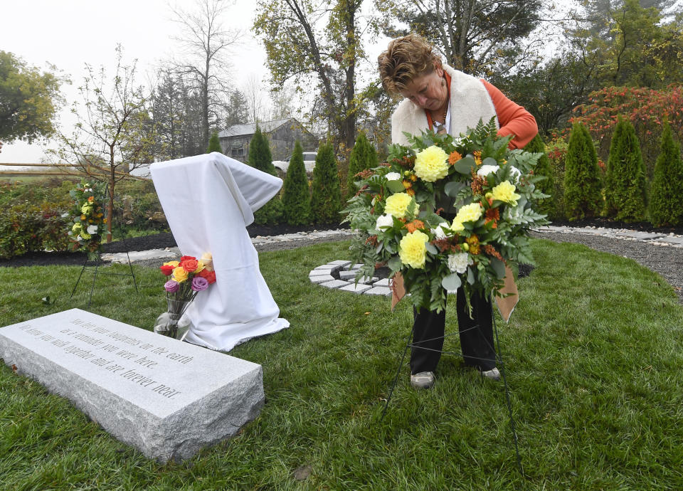 Lois Goblet of Berne, N.Y., places floral wreaths at the Reflections Memorial before family members and friends gather for a memorial unveiling ceremony, on the one year anniversary of the Schoharie limousine crash that killed 20 people next to the Apple Barrel Restaurant Saturday, Oct. 5, 2019, in Schoharie, N.Y. (AP Photo/Hans Pennink)