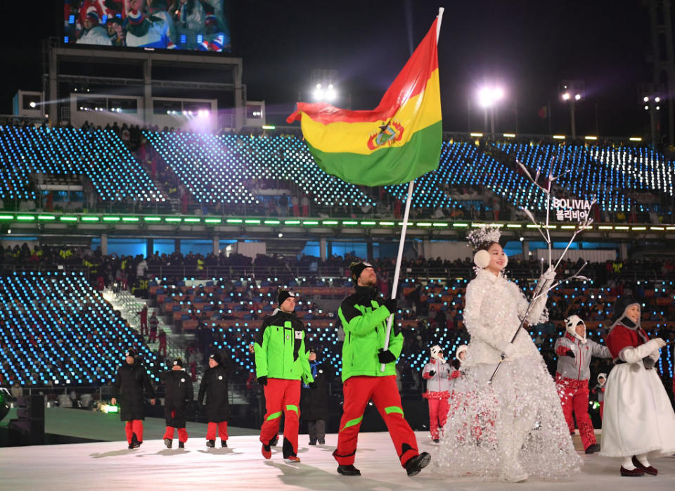 <p>Flag bearer Simon Breitfuss Kammerlander of Bolivia leads out his country, who all wear lime green ski jackets and red pants during the opening ceremony of the 2018 PyeongChang Games. (Photo: Quinn Rooney/Getty Images) </p>