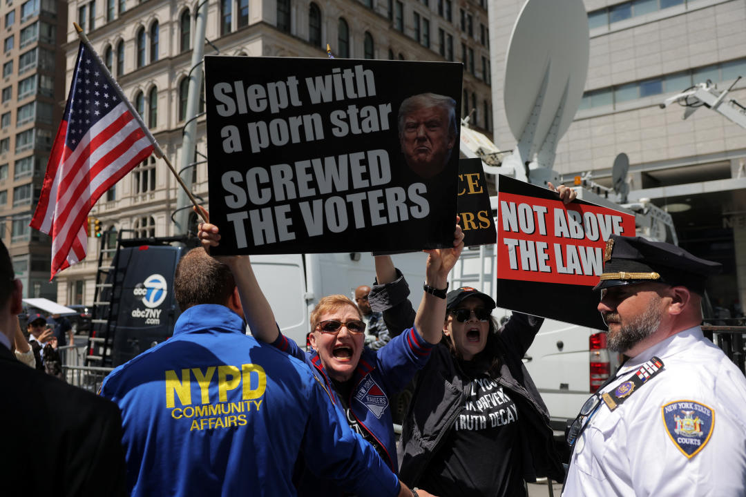Demonstrators hold signs reading: Slept with a porn star; screwed the voters, and Not above the law.