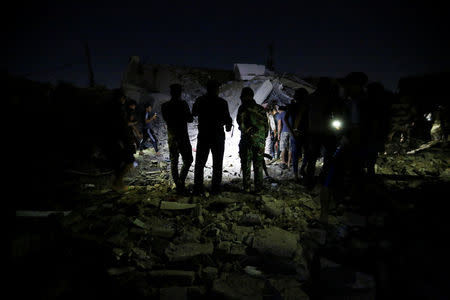 Iraqi security forces with people inspect the site of a car bomb attack in Sadr City district of Baghdad, Iraq June 6, 2018. REUTERS/Wissm al-Okili