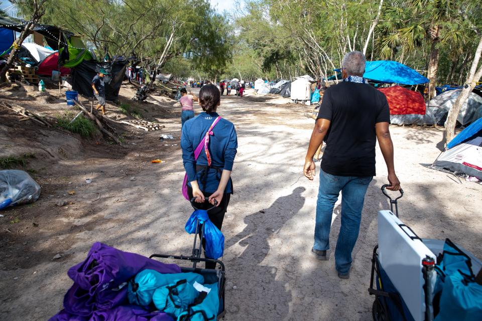 Volunteers with Acupuncturists Without Borders Victor Manuel and Rocio Lopez walk thought a migrant camp in Matamoros, Mexico.