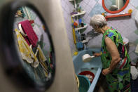Lyubov Mahlii, 76, washes towels in her bathtub with water dragged up four flights of stairs from a public well nearby at her apartment in Sloviansk, Donetsk region, eastern Ukraine, Sunday, Aug. 7, 2022. Water she had gathered filled the plastic tubs and buckets stacked on every flat surface in her small bathroom, while empty plastic bottles lined the walls in her hallway. (AP Photo/David Goldman)