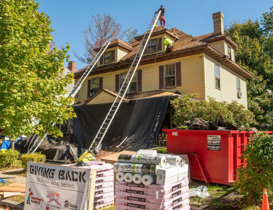 Workers replace the roof on the home of World War II veteran John H. Burke.