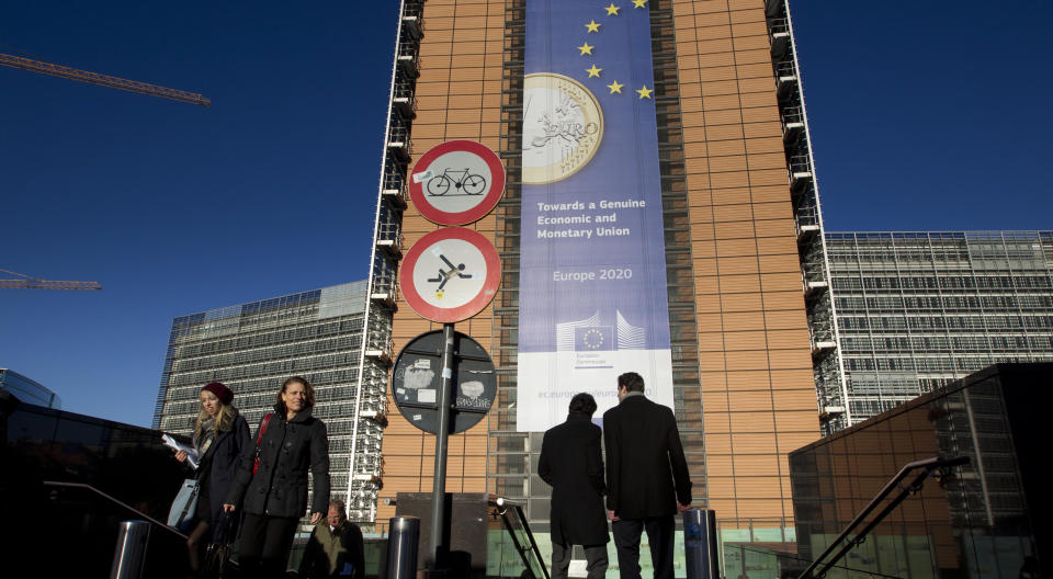 People walk in front of a giant banner for the euro currency outside of an EU summit in Brussels on Thursday, Nov. 22, 2012. Leaders from around Europe are arriving in Brussels Thursday for what promises to be a turbulent summit on the budget for the 27-country European Union. And for once, Britain will be at the heart of the debate. (AP Photo/Virginia Mayo)