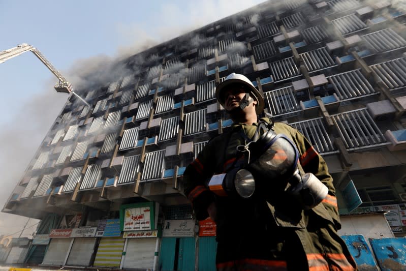 A fireman is seen as firemen hose down a burning building in Baghdad
