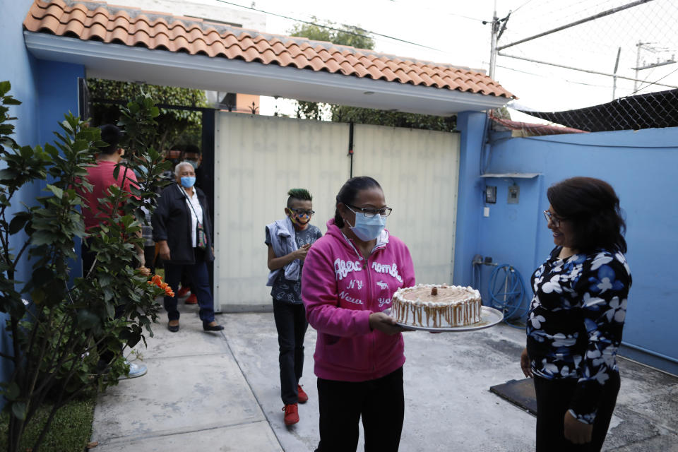 Marta Patricia Hernandez Santos, right, welcomes her sister's family and her mother, as they arrive for a small gathering at home to mark the 15th birthday of her daughter, Ximena Canejo Hernandez, in Tlalnepantla, just outside Mexico City, Monday, July 13, 2020. Another sister, a nurse in a COVID-19 hospital, did not attend to reduce the risk of coronavirus spread. Ximena's family, wanting to give her a traditional Quinceanera, had booked a church and event hall for July 18th long before the coronavirus pandemic hit, but the celebration had to be postponed until late November. (AP Photo/Rebecca Blackwell)