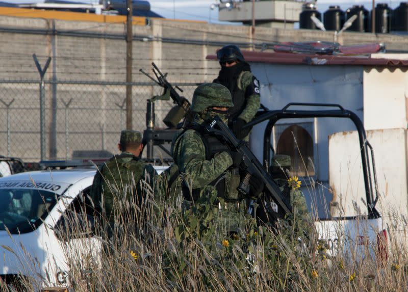 Members of the Mexican National Guard stand atop a vehicle as they keep watch outside the prison after sixteen inmates were killed and five were wounded in a prison fight at the Regional Center for Social Reintegration in the town of Cieneguillas