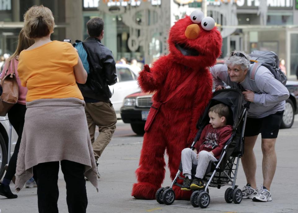 An Elmo character poses for photos in New York's Times Square,  Tuesday, April 9, 2013.  A string of arrests in the last few months has brought unwelcome attention to the growing number of people, mostly poor immigrants, who make a living by donning character outfits, roaming Times Square and charging tourists a few dollars to pose with them in photos. (AP Photo/Richard Drew)