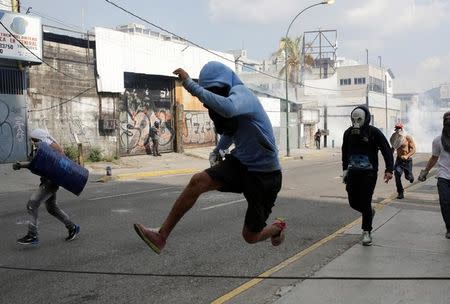 Opposition supporter jumps over a chain set up over the street while running from tear gas during a rally against Venezuela's President Nicolas Maduro in Caracas, Venezuela, April 26, 2017. REUTERS/Marco Bello