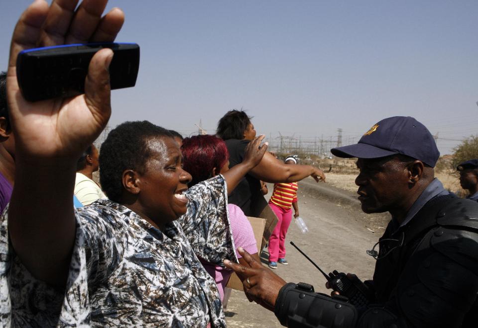 An unidentified woman protests against the police near a shooting scene at the Lonmin mine near Rustenburg, South Africa, Friday, Aug. 17, 2012. Police chief Mangwashi Victoria Phiyega says 34 miners died and another 78 were wounded when police opened fire on strikers in one of the worst police shootings in South Africa since apartheid. (AP Photo/Themba Hadebe)