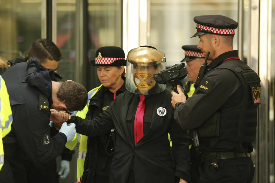 Police remove a Extinction Rebellion climate protester after they formed a line and glued themselves to the entrances of the London Stock Exchange in the City of London, Thursday April 25, 2019. (Isabel Infantes/PA via AP)