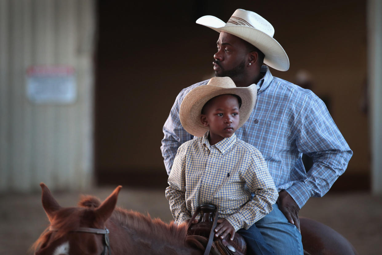 Cowboy Sayings pictured: Black cowboy and his son ride horse together | (Photo by Scott Olson/Getty Images)