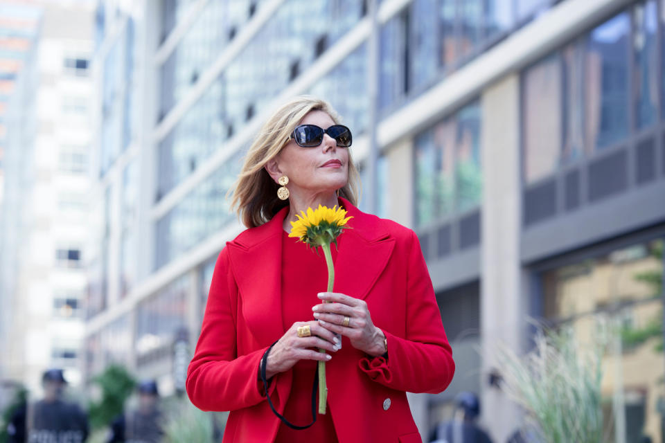 a woman standing in a city street holding a flower