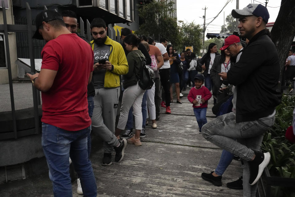 Personas aguardan en el exterior de la embajada de Venezuela en Quito, Ecuador, el martes 16 de abril de 2024. El presidente venezolano, Nicolás Maduro, ordenó el cierre de la embajada y de los consulados de su país en Ecuador en solidaridad con México y como rechazo a la irrupción de la policía ecuatoriana en la embajada de México en Quito. (AP Foto/Dolores Ochoa)