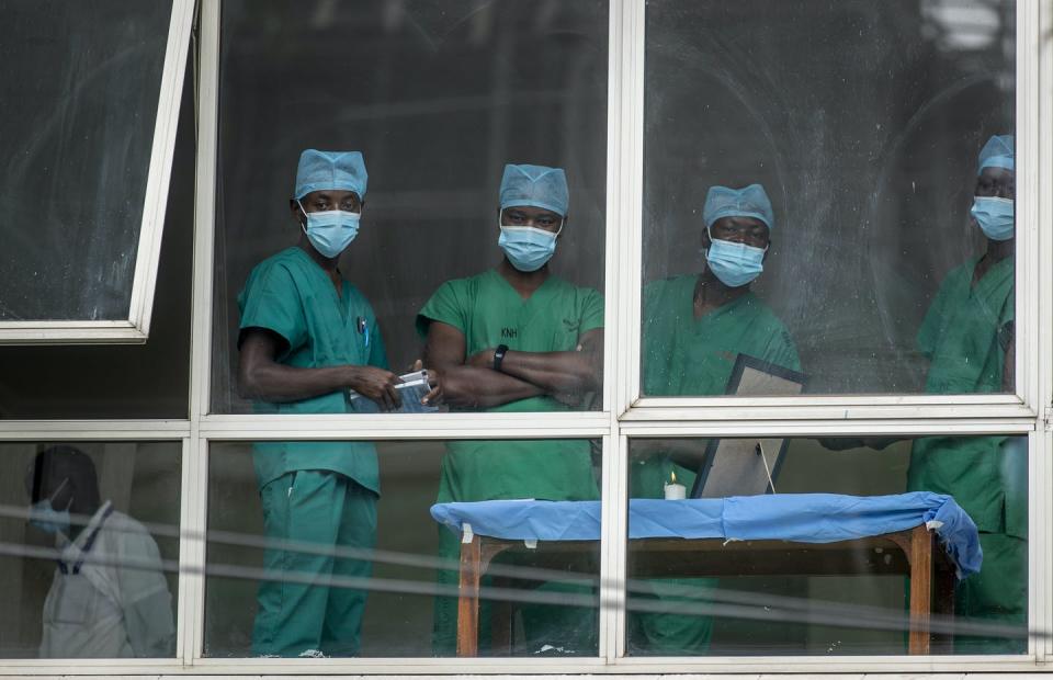 Medical staff wearing masks look out of a hospital window.