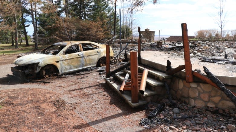 The remains of a cottage and the burnt shell of a decommissioned RCMP cruiser are seen at a property in Portapique, N.S., that belonged to the gunman who killed 22 people on April 18 and 19. (Steve Lawrence/CBC)