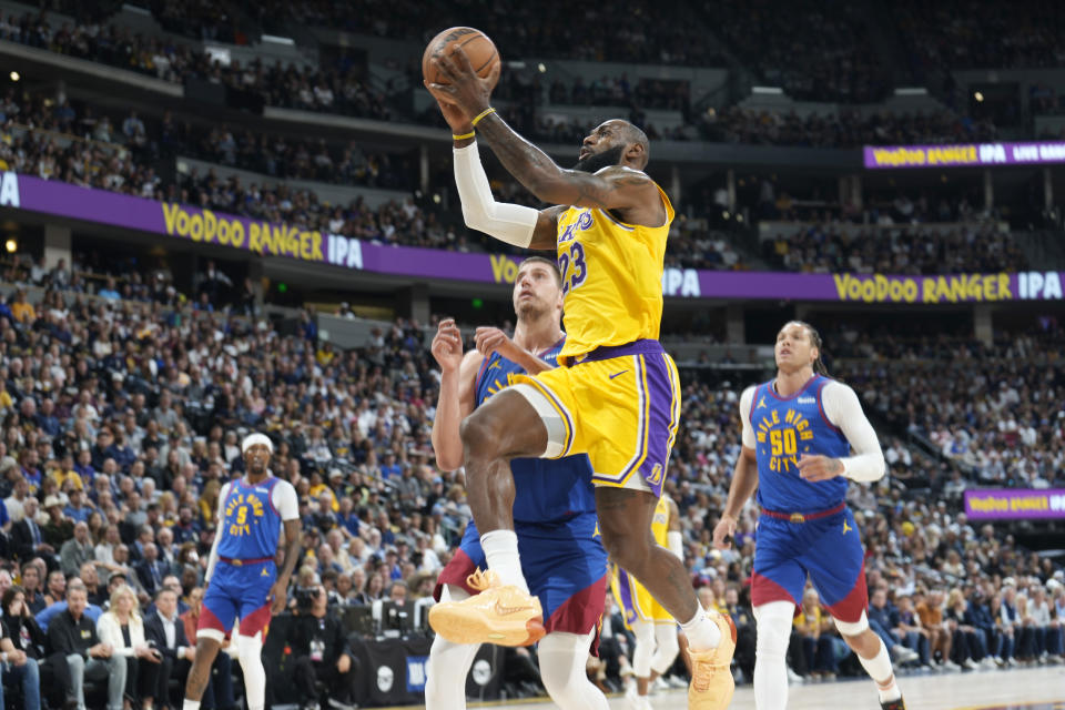 Los Angeles Lakers forward LeBron James drives to the basket past Denver Nuggets center Nikola Jokic and forward Aaron Gordon, right, during the first half of an NBA basketball game Tuesday, Oct. 24, 2023, in Denver. (AP Photo/David Zalubowski)