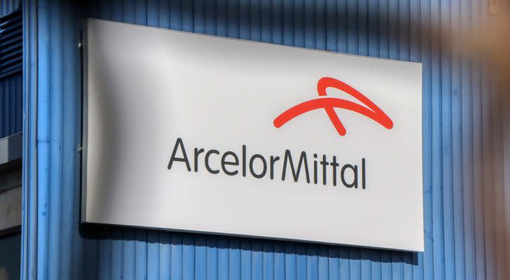 The logo for ArcelorMittal SA (MT) is displayed on a large sign on a blue wall.