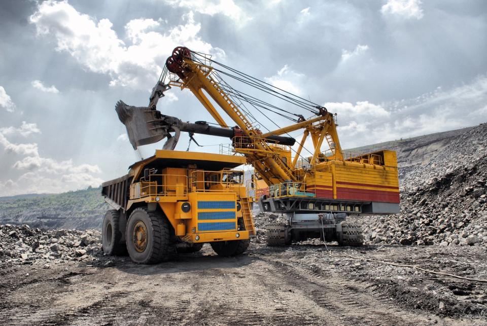 An excavator placing payload into the back of a dump truck in an open-pit mine. 