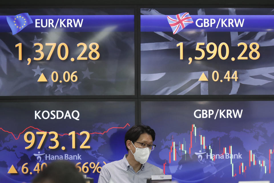 A currency trader walks near screens showing the Korean Securities Dealers Automated Quotations (KOSDAQ), left bottom, and the foreign exchange rates at a bank's foreign exchange dealing room in Seoul, South Korea, Monday, May 17, 2021. Asian stock markets were mixed Monday after Taiwan and Singapore tightened anti-coronavirus restrictions and Wall Street turned in its biggest weekly decline in three months. (AP Photo/Lee Jin-man)