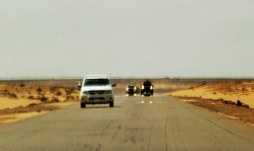 Libyan forces loyal to Moamer Kadhafi (black, background) chase a pick-up truck (white, foreground) and the car from which the photo is taken, carrying AFP journalists Dave Clark and photographer Roberto Schmidt and Getty Images photographer Joe Raedle, minutes before being arrested by the Moamer Kadhafi loyalists