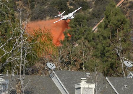 An air tanker makes waters drops as firefighters battle a fast-moving California wildfire, so-called the "Colby Fire", in the hills of Glendora January 16, 2014. REUTERS/Gene Blevins