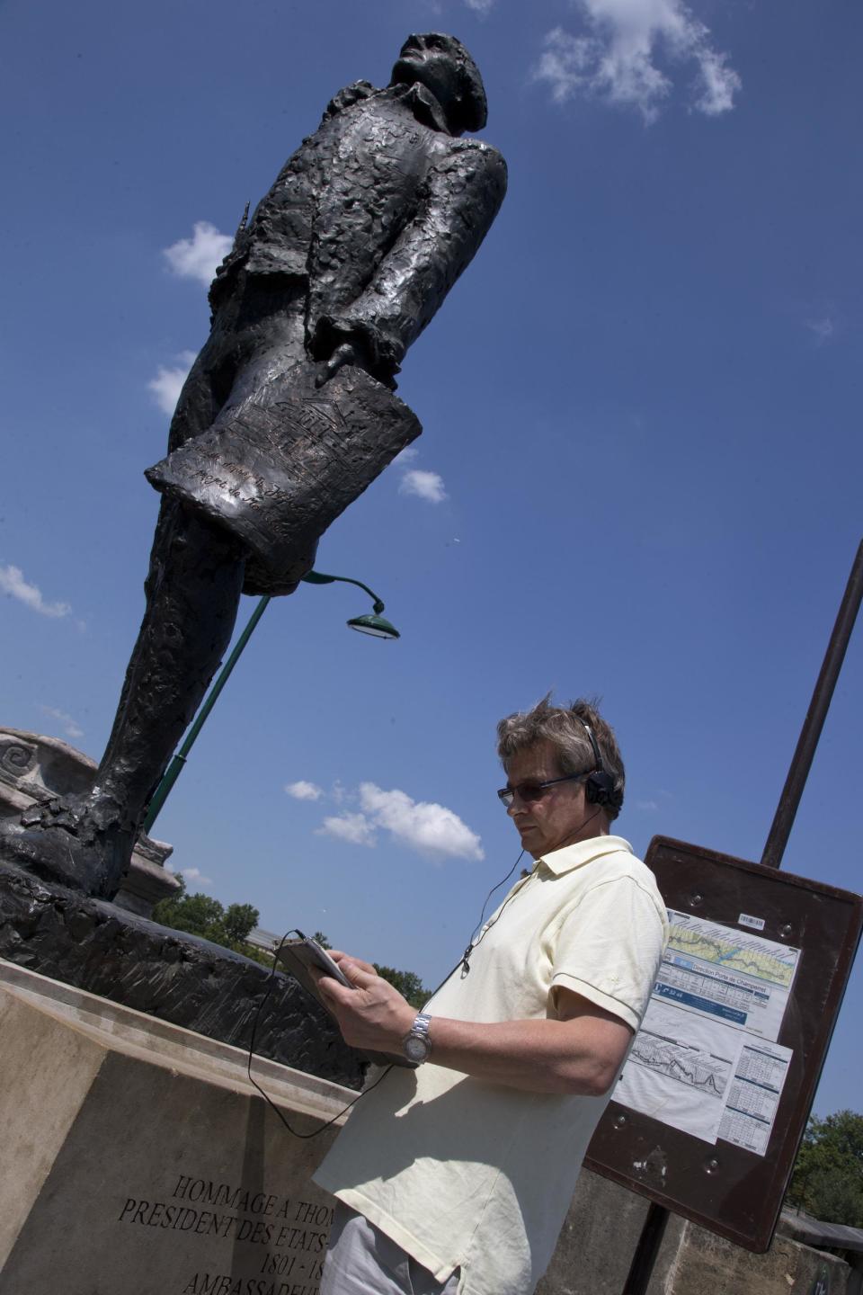 In this photo taken Friday, July 19, 2013, a tourist uses an iPad application under Thomas Jefferson Statue next to Musée d'Orsay during a Guided Tour around the main spots of the Revolutonary-era American presence on Paris' left bank, in Paris, France. (AP Photo/Francois Mori)