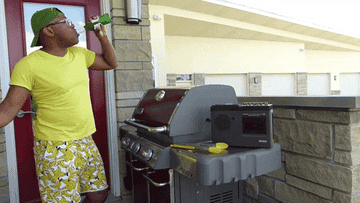 Man drinking a beer while grilling outside