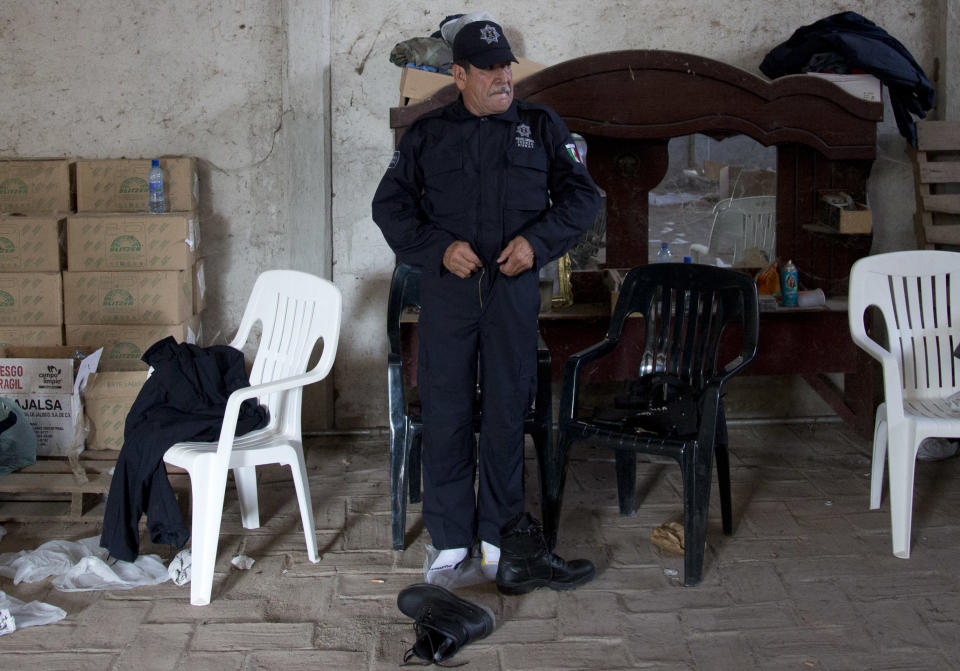 A member of a self-defense group puts on his newly-issued police uniform, before the start of a ceremony in Tepalcatepec, Mexico, Saturday, May 10, 2014. At the ceremony in the town where the vigilante movement began in February 2013, officials handed out new pistols, rifles and uniforms to 120 self-defense group members who were sworn into a new official rural police force. Mexico's government on Saturday began demobilizing the vigilante movement of assault-rifle-wielding ranchers and farmers that had succeeded in largely expelling the Knights Templar cartel from the western state of Michoacan when authorities couldn't. (AP Photo/Eduardo Verdugo)