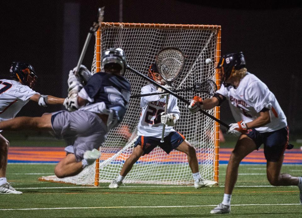 St. Edward's midfielder Reed Sternberg (27) attempts a leaping shot on goal, defended by Benjamin goalie Tatum Little (26) during the District 8-1A boys lacrosse championship game between St. Edward's and host Benjamin on April 13, 2023, in Palm Beach Gardens.