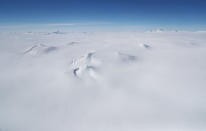 <p>Mountains (center) are mostly covered in ice as in this view from NASA’s Operation IceBridge research aircraft, in the Antarctic Peninsula region on Nov. 3, 2017, above Antarctica. (Photo: Mario Tama/Getty Images) </p>