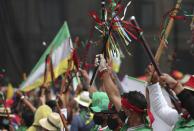 Indigenous hold up "bastones de mando," or leadership batons, as they march against the government in Bogota, Colombia, Monday, Oct. 19, 2020. The leaders of the Indigenous communities say they are mobilizing to reject massacres, assassinations of social leaders, criminalization of social protest, to defend their territory, democracy and peace, and plan to stay in the capital for a nationwide protest and strike on Oct. 21. (AP Photo/Fernando Vergara)