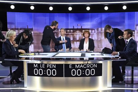 (From L) French presidential election candidate for the far-right Front National (FN) party, Marine Le Pen, French journalist Christophe Jakubyszyn, French journalist Nathalie Saint-Cricq and French presidential election candidate for the En Marche ! movement, Emmanuel Macron are prepared prior to the start of a live brodcast face-to-face televised debate in television studios of French public national television channel France 2, and French private channel TF1 in La Plaine-Saint-Denis, near Paris, France, May 3, 2017. REUTERS/Eric Feferberg/Pool