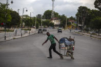 A man pulls a loaded shopping cart through a street, empty due to a general strike in Port-au-Prince, Haiti, Monday, Oct. 18, 2021. Workers angry about the nation's lack of security went on strike in protest two days after 17 members of a US-based missionary group were abducted by a violent gang. (AP Photo/Joseph Odelyn)