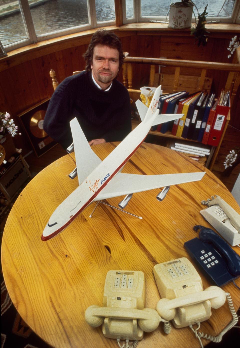 Richard Branson photographed in London in March 1984 sitting at a table with a model of a Virgin Atlantic Airways Boeing 747.