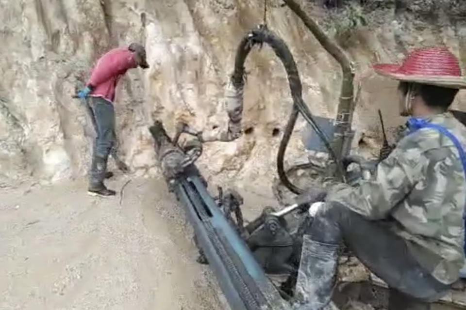 In this 2022 image from video provided by Global Witness, holes are drilled into the side of a mountain in the Kachin state of Myanmar, to mine rare earth minerals. Ammonium sulphate solution is injected into the holes, effectively liquefying the earth. Once the chemicals have percolated through the mountainside, the solution is drained into bright blue collection pools, where minerals are precipitated out. (Global Witness via AP)