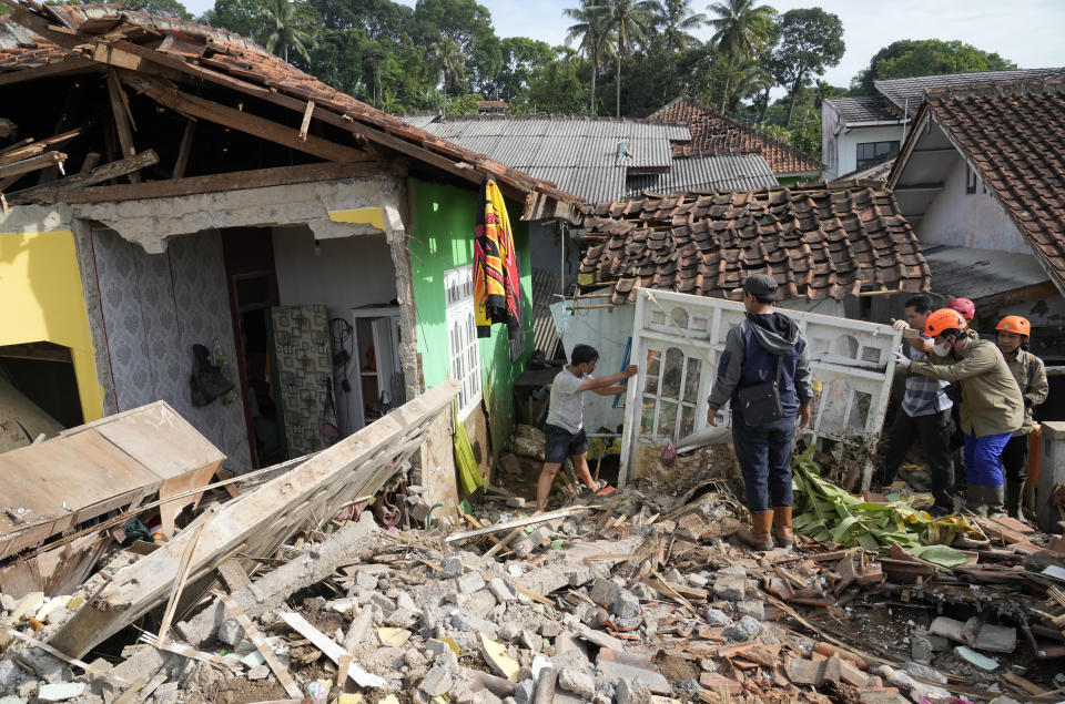 Rescuers help clear up debris from the ruins of a house damaged during Monday's earthquake in Cianjur, West Java, Indonesia, Wednesday, Nov. 23, 2022. More rescuers and volunteers were deployed Wednesday in devastated areas on Indonesia's main island of Java to search for the dead and missing from an earthquake that killed hundreds of people. (AP Photo/Tatan Syuflana)