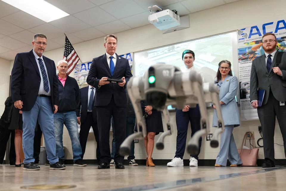 Jason Hoffman of Buckeye Educational Systems, left, watches as Ohio Lt. Gov. Jon Husted controls a quadruped robotic dog Monday during the grand opening of the Johnstown-Monroe High School Innovation Lab sponsored by Meta.