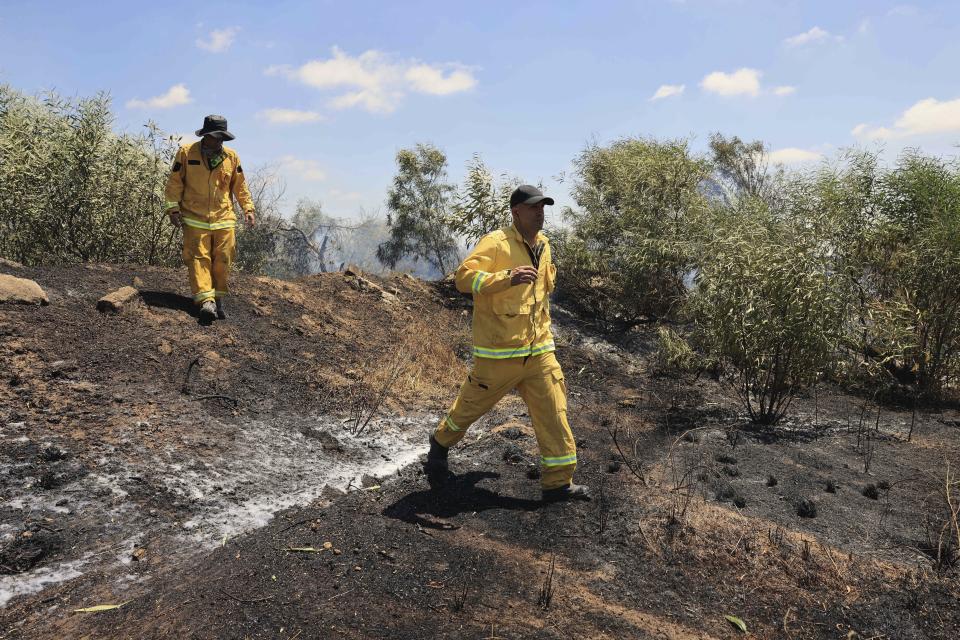 Israeli firefighters work at the site of a fire on the Israeli side of the border between Israel and Gaza, near Kibbutz Zikim, Friday, Aug. 21, 2020. Palestinian militants fired 12 rockets at Israel from the Gaza Strip overnight, nine of which were intercepted, and Israel responded with three airstrikes on targets linked to the territory's militant Hamas rulers, the Israeli military said early Friday. (AP Photo/Tsafrir Abayov)