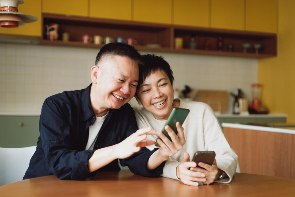 Asian couple using smartphone at home.