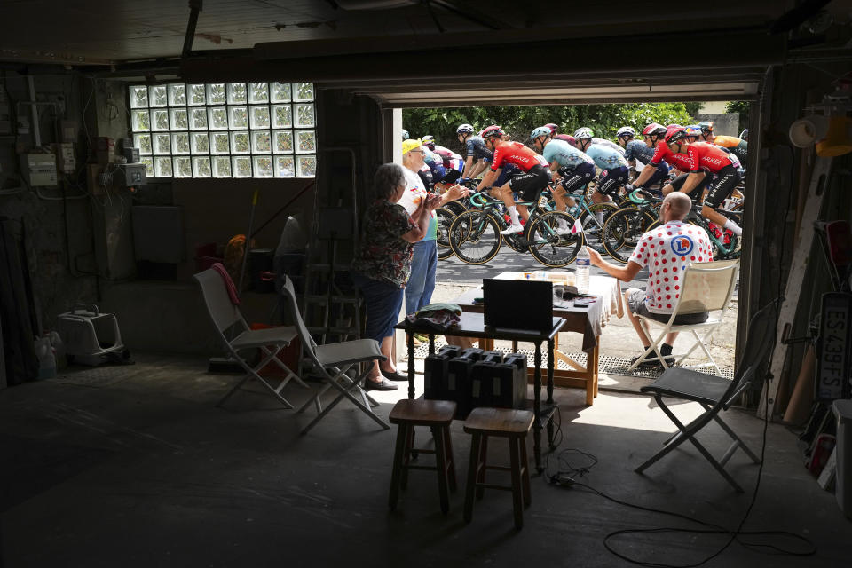 ADDS THAT THE PHOTO WAS TAKEN IN MENNETOUR SUR CHER - People watch the riders pass from their garage in Mennetou sur Cher during the tenth stage of the Tour de France cycling race over 187.3 kilometers (116.4 miles) with start in Orleans and finish in Saint-Amand-Montrond, France, Tuesday, July 9, 2024. (AP Photo/Daniel Cole)