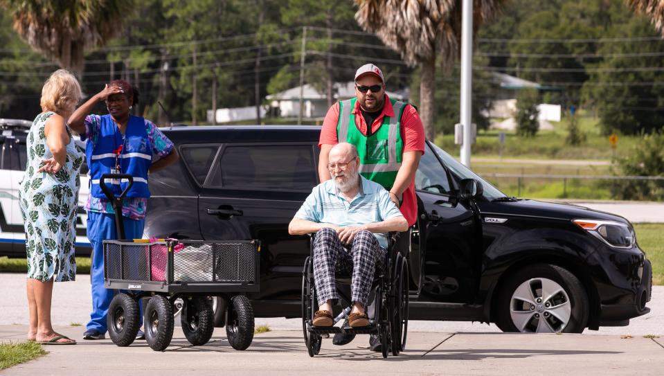 Mike Suarez brings David Harmon into the special-needs shelter at West Port High School on Tuesday.