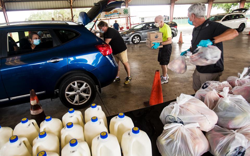 Yamile Vizcaino, a resident of Cape Coral watches as food from the Harry Chapin Food Bank mobile food pantry is delivered at  the Lee County Civic Center in North Fort Myers on Wednesday, May 20, 2020.