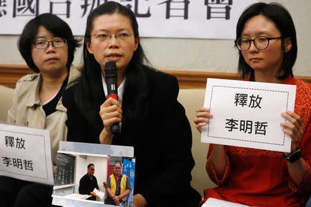 Li Ching-yu (C), holds photos of her husband, Taiwanese human rights activist Li Ming-che, detained in China, during a news conference in Taipei, Taiwan March 29, 2017. REUTERS/Tyrone Siu