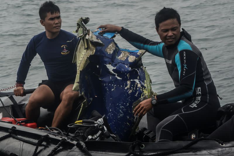 Indonesia Navy members carry recovered debris from Sriwijaya Air flight SJ 182 which crashed into the sea off the Jakarta coast