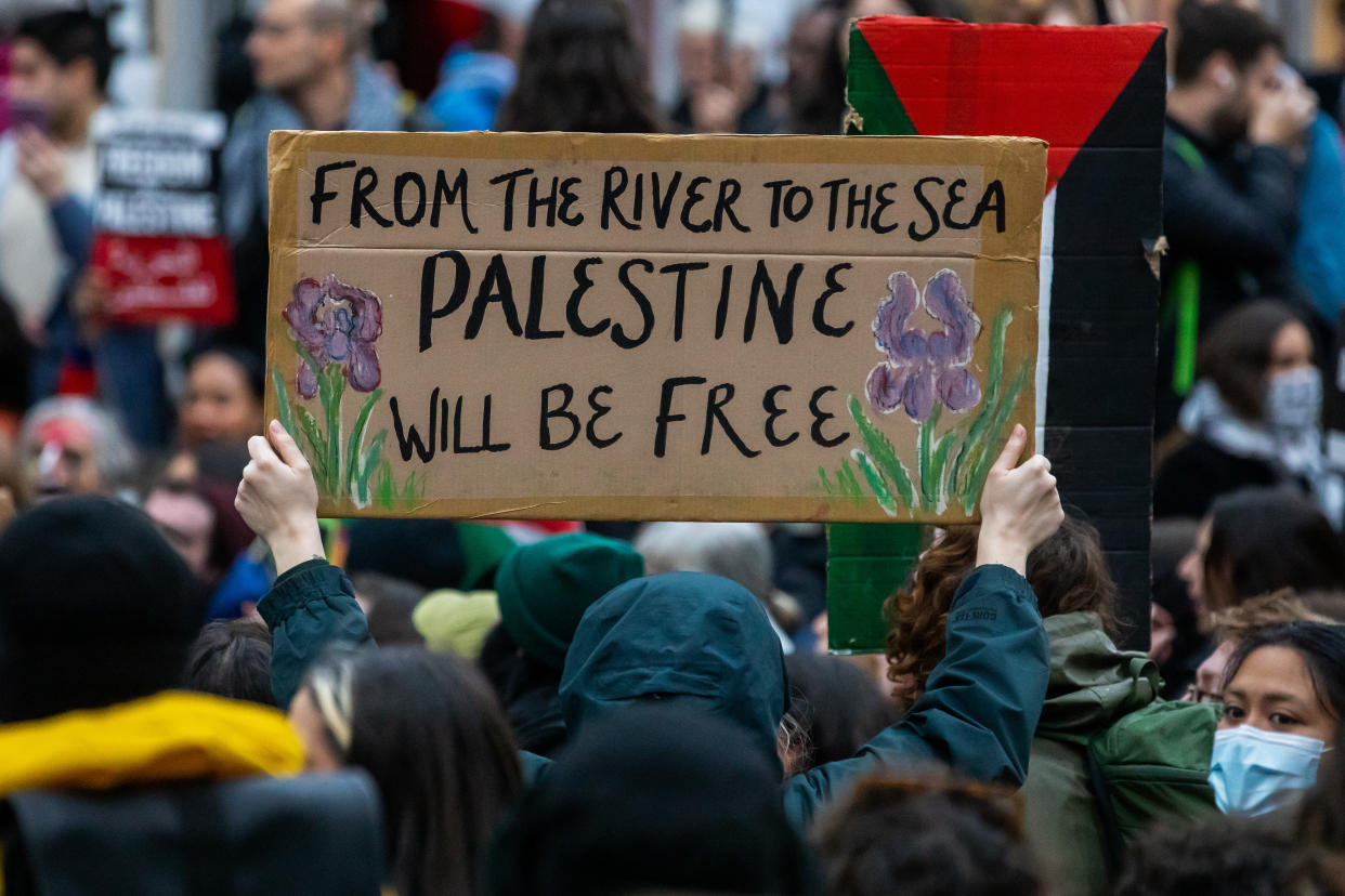  A pro-Palestinian activist holds up a sign reading 'From The River To The Sea Palestine Will Be Free'. 