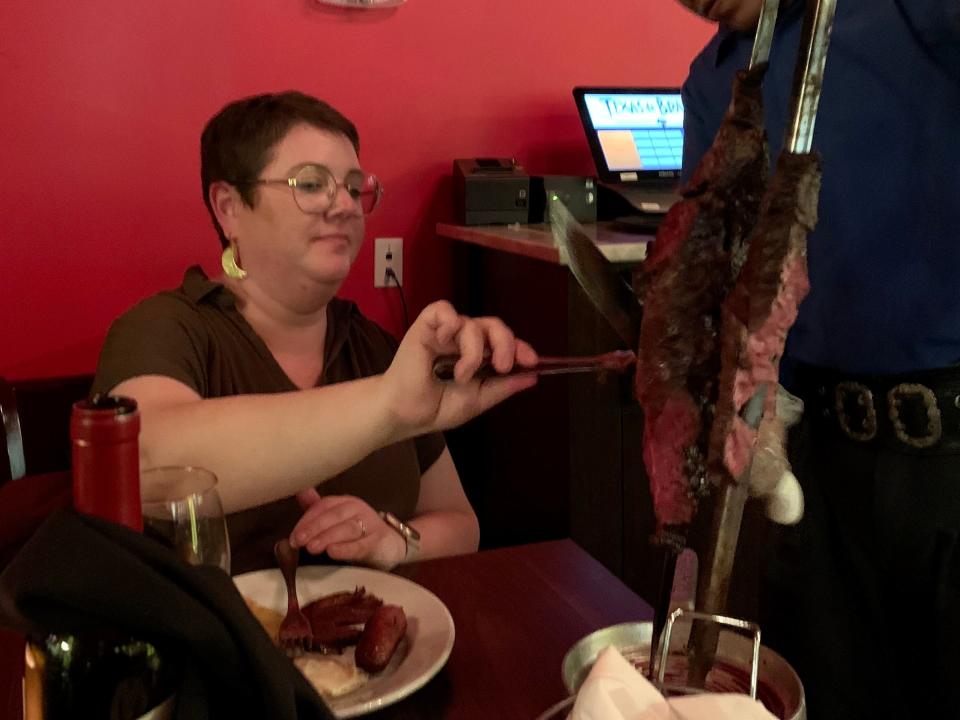 lauren grabbing meat off a skewer at texas de brazil steak house