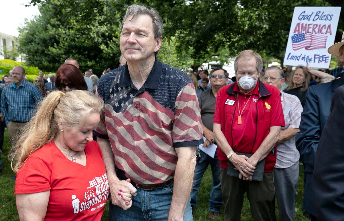 Sherry and Jim Womack of Lee County, N.C. and Carl Mischka of New Bern, N.C., right, pray during a Return America rally, calling on Governor Cooper to rescind his executive order prohibiting churches from holding indoor worship services on Thursday, May 14, 2020 on the Legislative grounds in Raleigh, N.C.