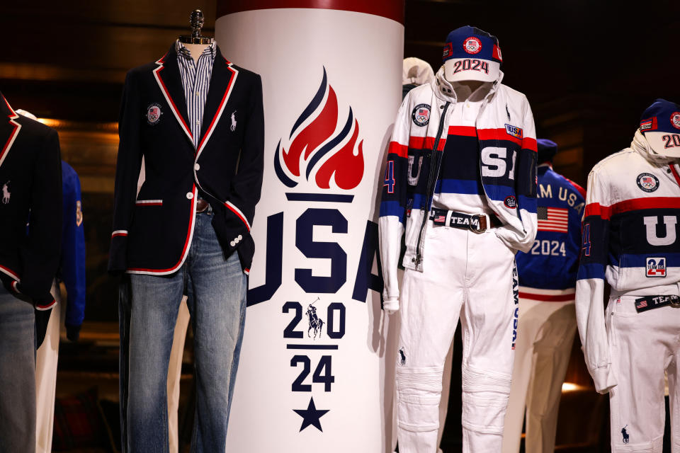 Display of Team USA 2024 Olympic uniforms featuring a mannequin in a blazer and jeans, another in a white tracksuit, and another in branded attire